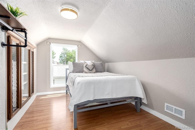 1946 Xenia St, Denver, CO 80220 - bedroom with a textured ceiling, light wood-style floors, lofted ceiling, and a textured wall