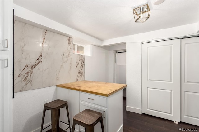 1946 Xenia St, Denver, CO 80220 - kitchen with butcher block countertops, dark wood-style flooring, white cabinetry, and a peninsula