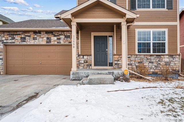 snow covered property entrance with a garage