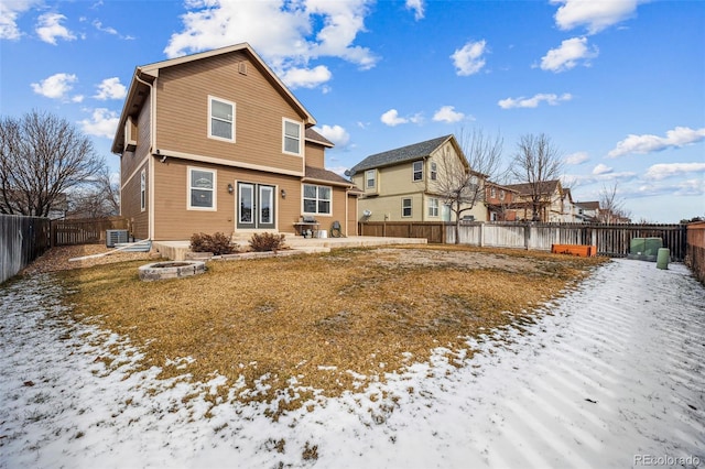 snow covered rear of property featuring central AC unit and a patio area