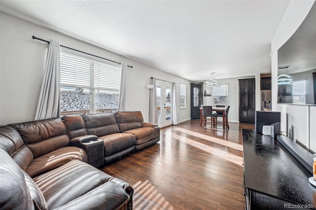 living room with a textured ceiling, dark hardwood / wood-style flooring, and french doors