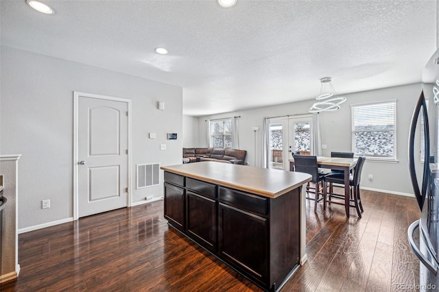 kitchen with a center island, french doors, dark wood-type flooring, stainless steel fridge, and dark brown cabinets