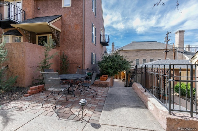 view of patio featuring a balcony and fence