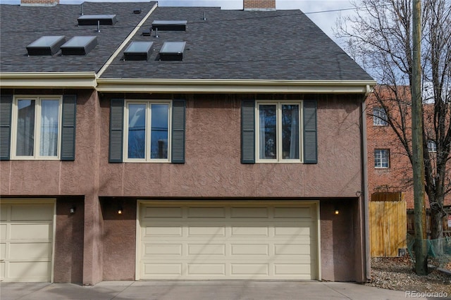 rear view of house featuring stucco siding, concrete driveway, a garage, and a shingled roof