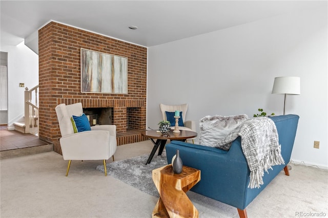 carpeted living area with baseboards, stairs, and a brick fireplace