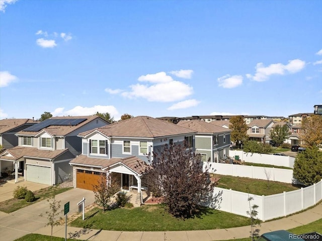 view of front of home featuring a front lawn, solar panels, and a garage