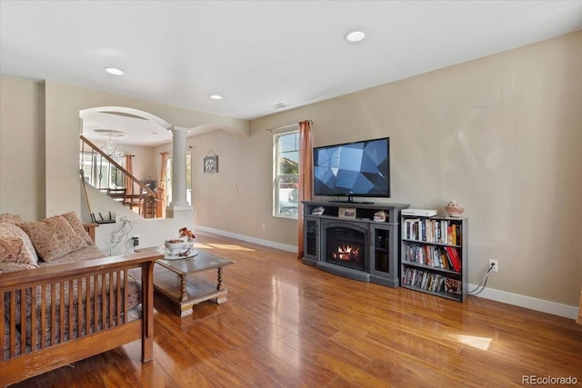 living room featuring ornate columns, a fireplace, and wood-type flooring