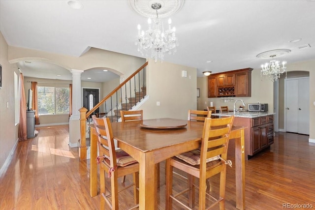 dining area featuring decorative columns, hardwood / wood-style floors, and a chandelier