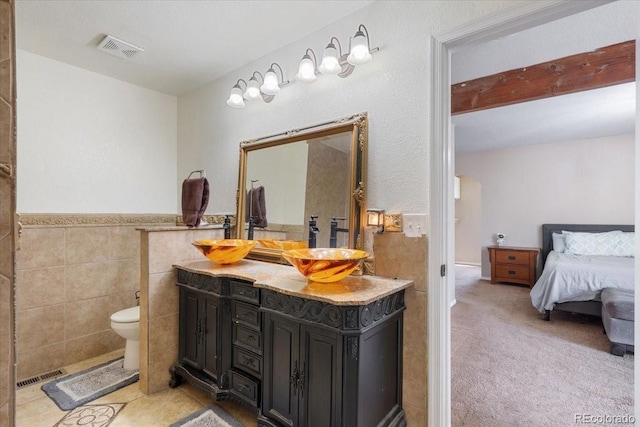 bathroom with toilet, vanity, and tile walls