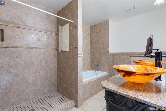 bathroom featuring vanity, tile patterned flooring, tile walls, and plus walk in shower