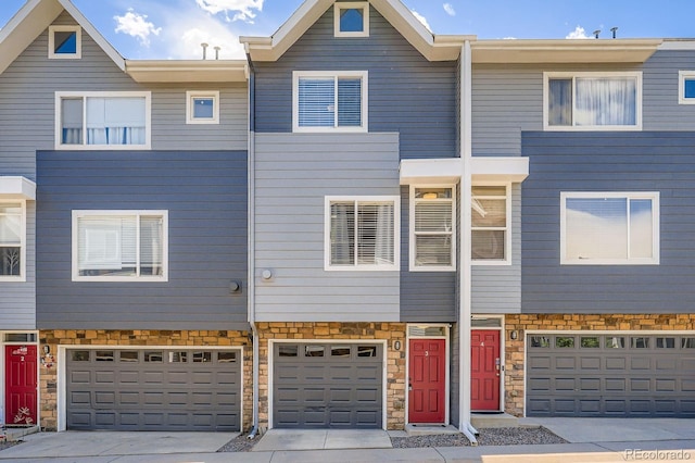 8751 Pearl St Unit J3, Thornton, CO 80229 - view of property featuring stone siding, driveway, and an attached garage