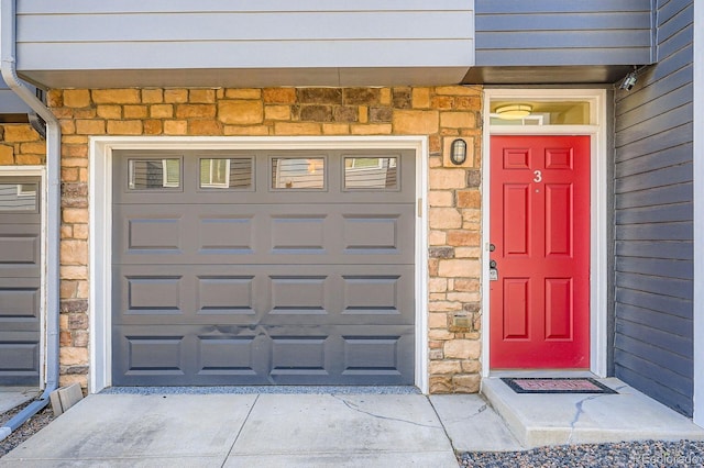 8751 Pearl St Unit J3, Thornton, CO 80229 - property entrance with stone siding, concrete driveway, and a garage