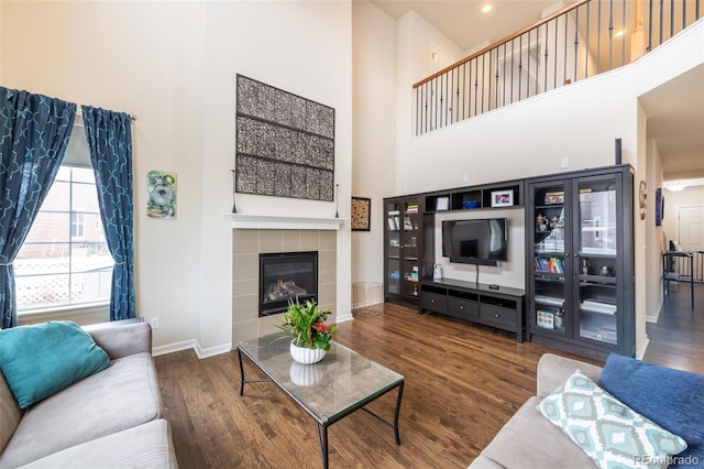 living room with a fireplace, dark wood-type flooring, and a high ceiling