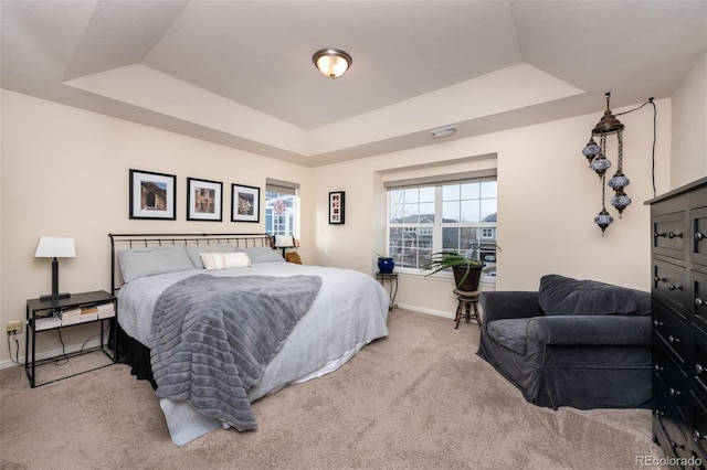 bedroom featuring light colored carpet and a raised ceiling