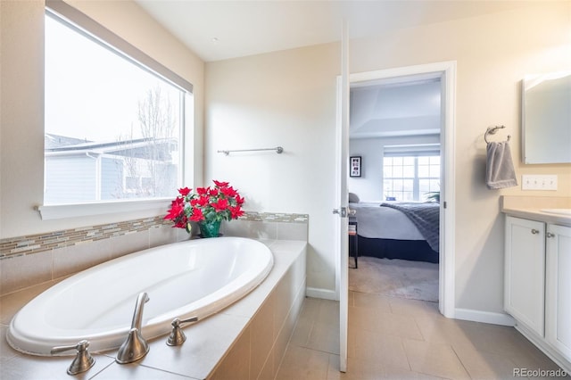 bathroom featuring tile patterned flooring, vanity, and a relaxing tiled tub