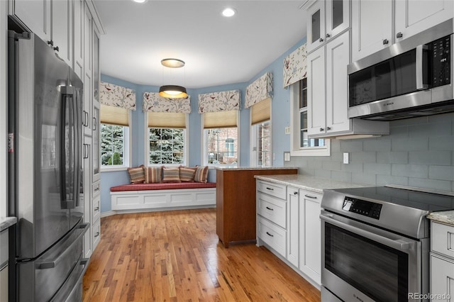 kitchen with decorative backsplash, appliances with stainless steel finishes, light stone counters, pendant lighting, and white cabinetry