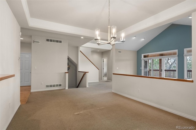 carpeted empty room with lofted ceiling and a notable chandelier