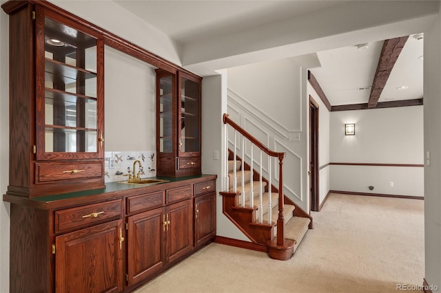 stairway with carpet, beam ceiling, and sink