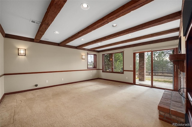 unfurnished living room with beamed ceiling, light carpet, and a healthy amount of sunlight