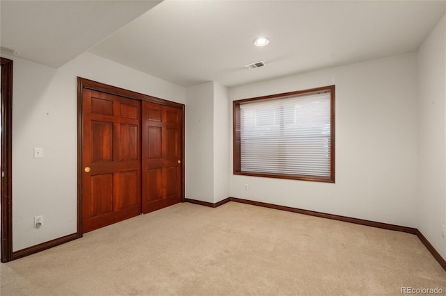 unfurnished bedroom featuring light carpet and a closet