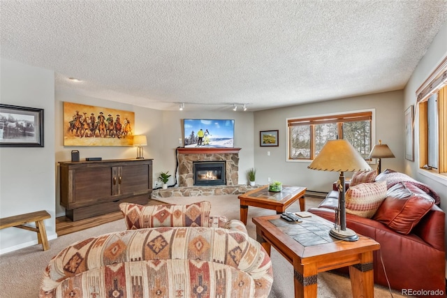 carpeted living room with a stone fireplace, track lighting, and a textured ceiling