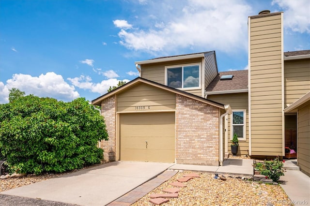 10309 W Fair Ave Unit E, Littleton, CO 80127 - view of front facade featuring driveway, brick siding, a chimney, and a garage