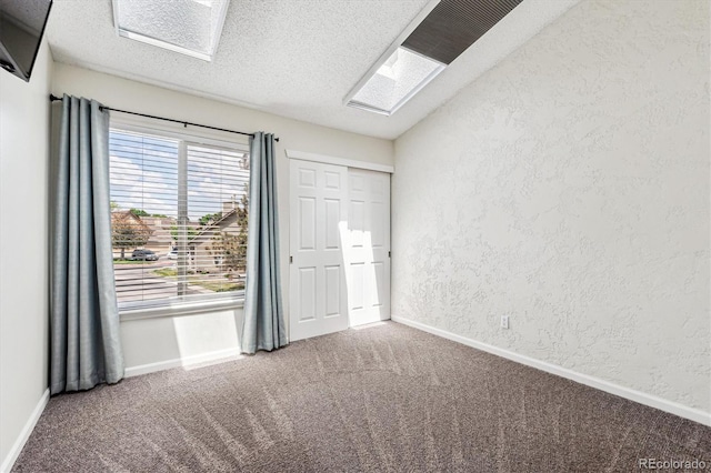 10309 W Fair Ave Unit E, Littleton, CO 80127 - unfurnished bedroom with carpet floors, a textured wall, a textured ceiling, baseboards, and a skylight