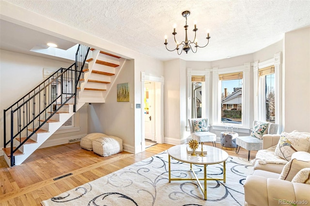 sitting room featuring a notable chandelier, visible vents, stairway, wood finished floors, and baseboards