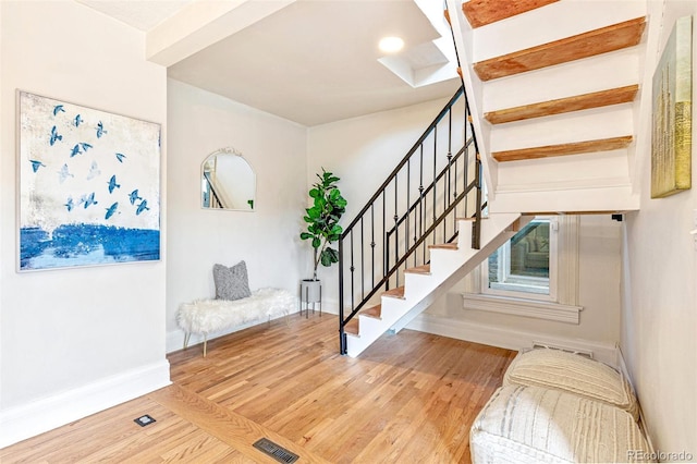 foyer featuring visible vents, stairway, baseboards, and wood finished floors