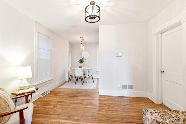 interior space with light wood finished floors, baseboards, visible vents, and an inviting chandelier