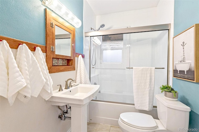 full bath with combined bath / shower with glass door, tile patterned flooring, and toilet