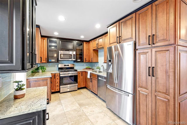 kitchen featuring stainless steel appliances, light tile patterned floors, brown cabinetry, and tasteful backsplash