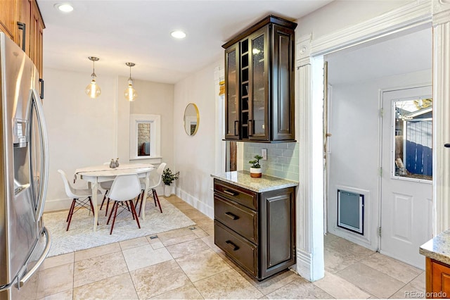 kitchen with light stone counters, recessed lighting, stainless steel fridge with ice dispenser, tasteful backsplash, and glass insert cabinets