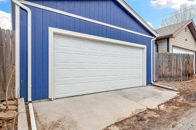 garage featuring driveway and fence