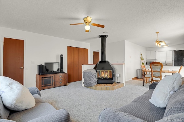5501 Denmark Ct, Colorado Springs, CO 80918 - living area featuring a wood stove, ceiling fan, carpet floors, and a textured ceiling