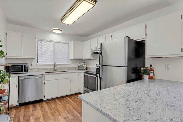 5501 Denmark Ct, Colorado Springs, CO 80918 - kitchen with stainless steel appliances, a sink, under cabinet range hood, white cabinetry, and light wood finished floors