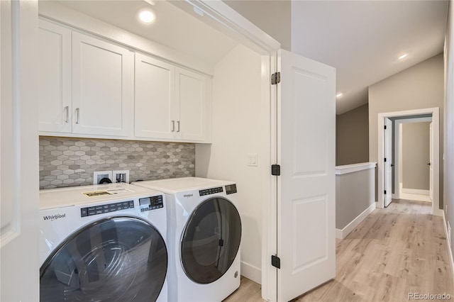 clothes washing area featuring cabinets, washing machine and dryer, and light wood-type flooring