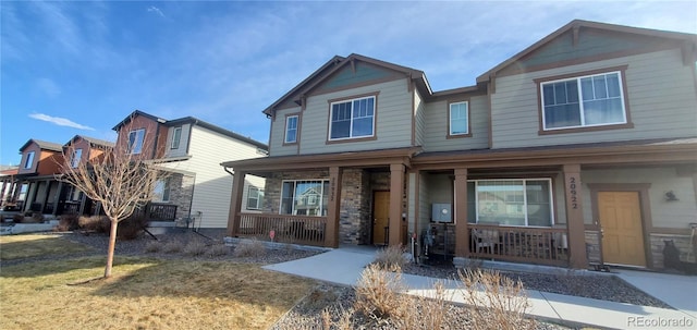 view of front of property with stone siding, covered porch, and a front yard