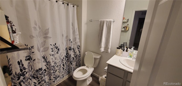 full bathroom with a shower with shower curtain, toilet, vanity, and a textured wall