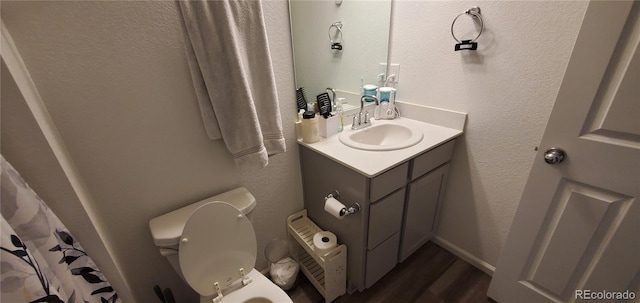 bathroom featuring vanity, toilet, wood finished floors, and a textured wall