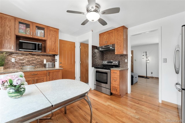 6545 Union St, Arvada, CO 80004 - kitchen with under cabinet range hood, stainless steel appliances, ceiling fan, and decorative backsplash