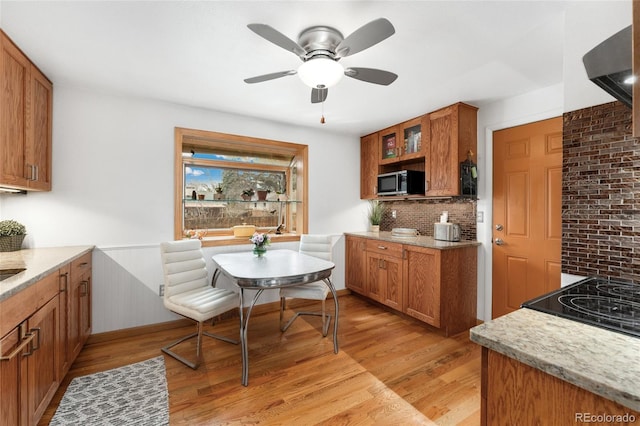 6545 Union St, Arvada, CO 80004 - kitchen with stainless steel microwave, backsplash, light wood-type flooring, and brown cabinetry