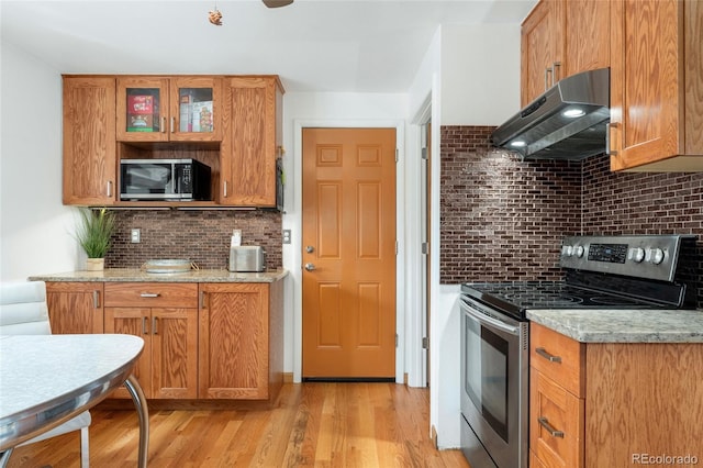 6545 Union St, Arvada, CO 80004 - kitchen featuring under cabinet range hood, appliances with stainless steel finishes, decorative backsplash, and light wood-style flooring