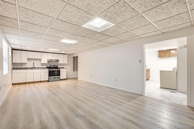 unfurnished living room featuring a paneled ceiling, sink, washer / clothes dryer, and light hardwood / wood-style flooring