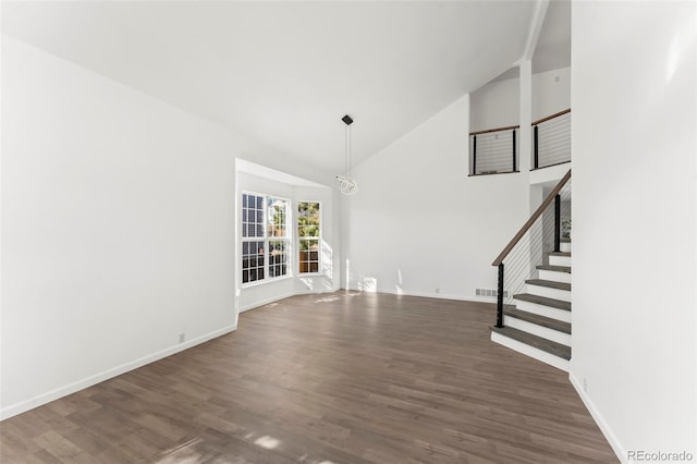 unfurnished living room with an inviting chandelier, high vaulted ceiling, and dark wood-type flooring