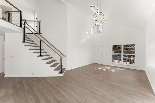 unfurnished living room with a chandelier, hardwood / wood-style floors, and high vaulted ceiling