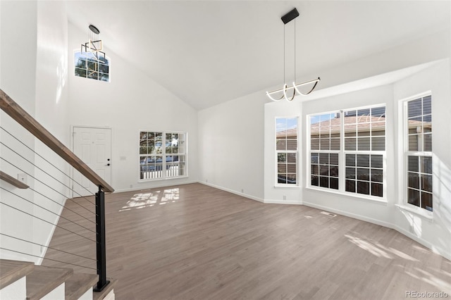 unfurnished living room with a chandelier, wood-type flooring, and high vaulted ceiling