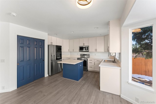 kitchen featuring white cabinets, a kitchen island, stainless steel appliances, and hardwood / wood-style flooring