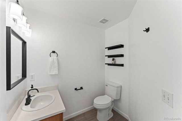 bathroom with wood-type flooring, vanity, and toilet