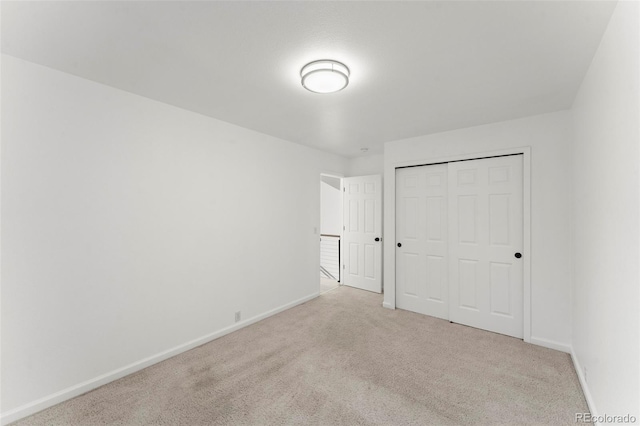 unfurnished bedroom featuring light carpet and a closet